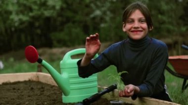 Beyaz çocuk bahçesinde bir yatakta. Çocuk bahar dikim yapmaktadır. Çocuk genç doğa yatağın yanında. Çocuk onun hands.Organic tarım bir fide ile.