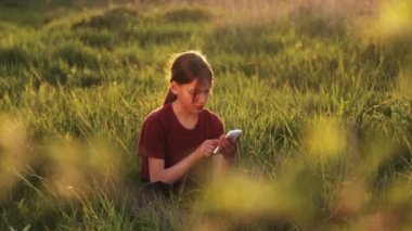 Doğa telefonda beyaz çocuk. Çocuk genç bir smartphone vasıl Günbatımı ile. Telefon fotoğrafları gün batımı ile çocuk. Doğa, insan ve teknoloji.