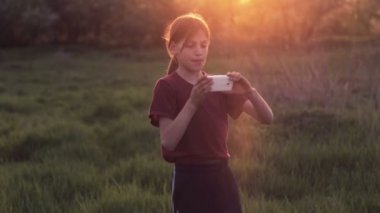 Doğa telefonda beyaz çocuk. Çocuk genç bir smartphone vasıl Günbatımı ile. Telefon fotoğrafları gün batımı ile çocuk. Doğa, insan ve teknoloji.