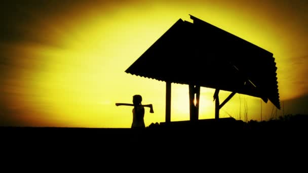 Silhouette eines Jungen bei Sonnenuntergang am alten Brunnen. Silhouette eines Kindes auf einem Feld bei Sonnenuntergang. Teenager-Junge mit dem Werkzeug über die Natur. Natur, Kind, Silhouette, Sonnenuntergang. — Stockvideo
