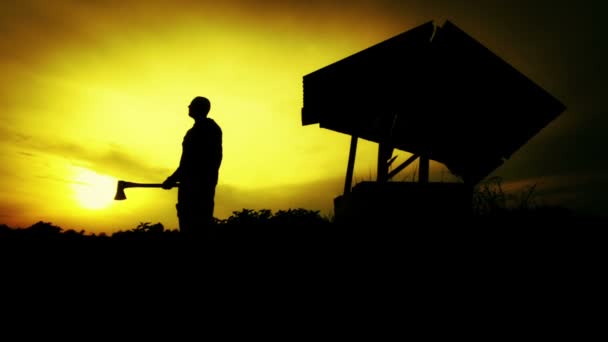 フィールドの日没時男のシルエット。古い井戸で斧を持つ男のシルエット。木こりの夕日でシルエットが、木こり。人間、自然、日没. — ストック動画