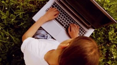 Bir dizüstü bilgisayar (yukarıdan) ile parkta beyaz çocuk. Bir çocuk ile bir dizüstü bilgisayarda doğa (Üstten Görünüm). Ülke çocuk genç ile laptop (Üstten Görünüm).