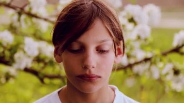 Portre yakın çekim, bahar bahçe beyaz tenli çocukta. İlkbaharda yemyeşil bir bahçe içindeki beyaz çocuk. Bahar çiçekleri çocuk yüz.