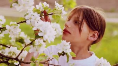 Portre yakın çekim, bahar bahçe beyaz tenli çocukta. İlkbaharda yemyeşil bir bahçe içindeki beyaz çocuk. Bahar çiçekleri çocuk yüz.