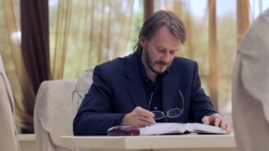 Caucasian man reading a book in the café. Portrait of a young man with a book in the restaurant. Stylish young man. Education, Lifestyle.