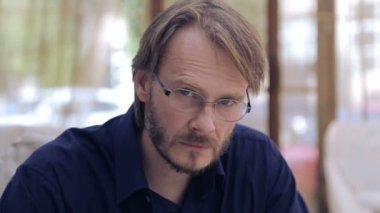 Kameraya bakan gözlüklü beyaz adam. Duygusal bir adamın portresi. Şık bir genç adamın yüzü yakın.