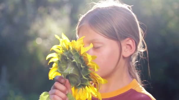 Retrato de un niño con una flor de girasol. Adolescente caucásica con gran flor de girasol. Adolescente Boy oliendo una flor de girasol . — Vídeos de Stock