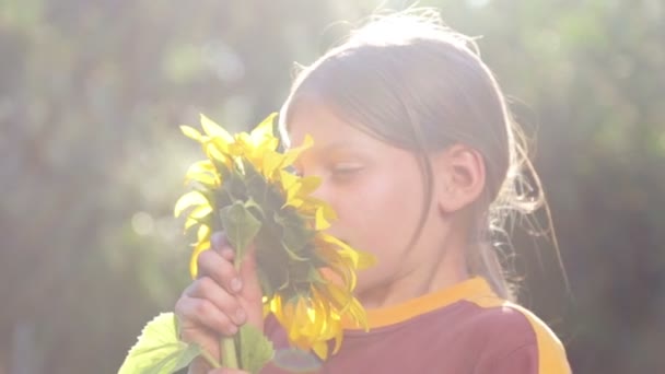 Retrato de un niño con una flor de girasol. Adolescente caucásica con gran flor de girasol. Adolescente Boy oliendo una flor de girasol . — Vídeos de Stock