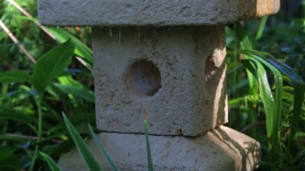 Japanese garden lantern in the rain. Raindrops falling on the Japanese stone lantern. — Stock Video