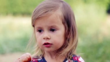 Beyaz küçük kız sosis mangal yiyor. Çocuk bir kız doğada yiyor. Emotsonalny çocuk sağlıklı gıda iştah açıcı yiyor. Bir yemek için bir çocuk portresi.