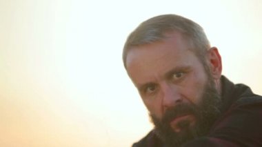 Sigarayla sakallı bir adam portresi. Duygusal adam kameraya sigara içiyor..