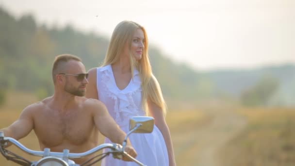 Man and woman on a motorcycle outdoors. In love with a young beautiful couple on a motorcycle in the country. — Stock Video