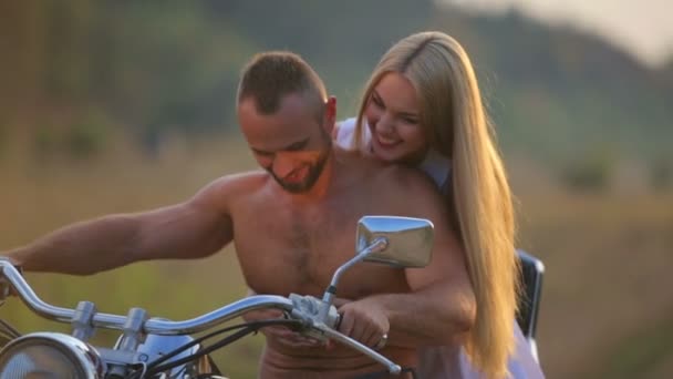 Man and woman on a motorcycle outdoors. In love with a young beautiful couple on a motorcycle in the country. — Stock Video