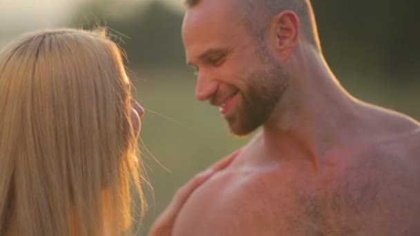 Un hombre y una mujer jóvenes en el parque al atardecer. Feliz pareja joven disfrutando de un momento íntimo en la naturaleza. Retrato de una joven pareja abrazándose y besándose . — Vídeos de Stock