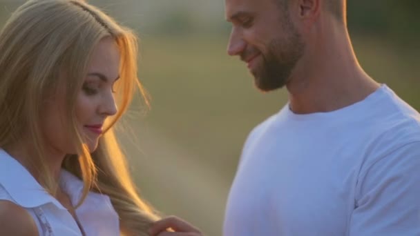Un giovane uomo e una donna nel parco al tramonto. Felice giovane coppia godendo di un momento intimo sulla natura. Ritratto di una giovane coppia che abbraccia e bacia . — Video Stock