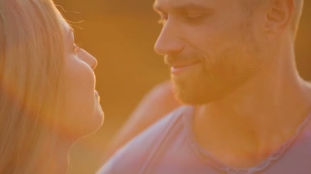 Um jovem e uma mulher no parque ao pôr-do-sol. Jovem casal feliz desfrutando de um momento íntimo sobre a natureza. Retrato de um jovem casal abraçando e beijando . — Vídeo de Stock