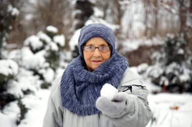 Kışın kartopu oynayan yaşlı bir kadının portresi. Yaşlı bir kadın kışın kartopu oynar..