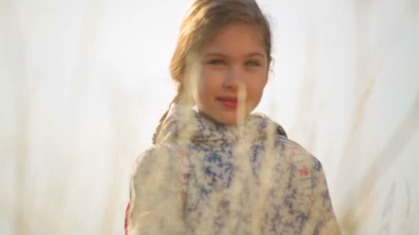 Ένα παιδί σε ένα χωράφι στην ύπαιθρο. Πορτρέτο ενός κοριτσιού κοντά. — Αρχείο Βίντεο