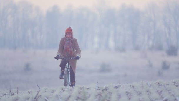 Kaukasisk kvinna i fältet av cykling. Ung kvinna cyklar över fältet. — Stockvideo