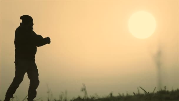 Un uomo caucasico che riposa in isolamento all'alba. Un giovane uomo in un campo all'alba . — Video Stock