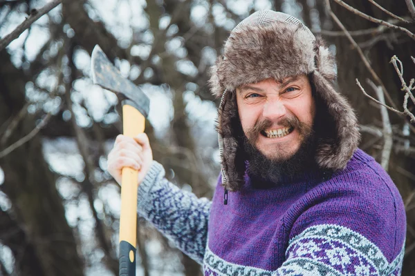 Retrato de um homem barbudo com um machado na mão. Homem barbudo brutal com um machado. Homem barbudo do norte com um machado na floresta . — Fotografia de Stock