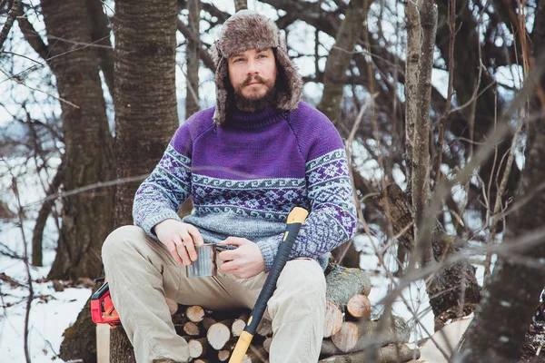 Bearded man drinking tea in the forest.Bearded woodcutter at rest in winter.