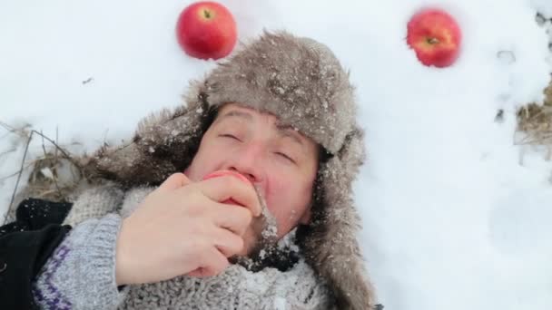 Portrait of a bearded man with an apple in the winter. A young bearded man eats an apple in the winter. The bearded man eating an apple to the camera in the winter. — Stock Video