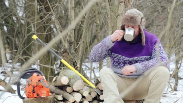Бородатый мужчина пьет чай в лесу. Бородатый дровосек отдыхает зимой . — стоковое видео