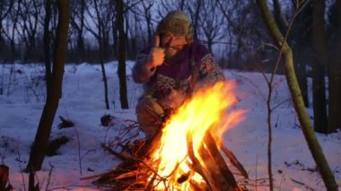 Sakallı adam ellerini ateşin yanında kışın ısınma. Turist adam akşam kamp ateşi. Ormanda bir yangın bir genç sakallı adama.