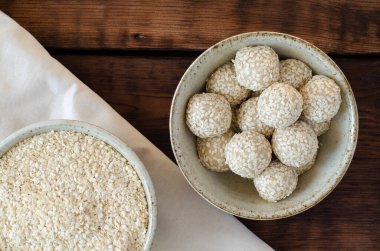 Susam tohumu topları ve keten ve ahşap arka planda kaselerde sıkılmış susam tohumları. Üst görünüm.