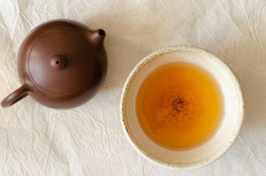 Kil bardakta yeşil çay ve keten arkaplanda kil çaydanlık. Üst görünüm.