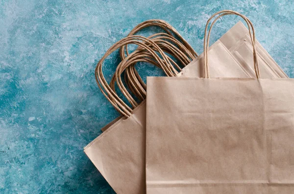 paper bags on abstract aqua blue background. Craft paper package with twisted handles.