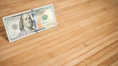 100 dolarlık banknot ve Benjamin Franklin 'in portresi. Ahşap arka planda 100 dolarlık banknotlar