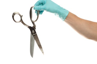 Doktorun eli eldivenli, beyaz arka planda izole edilmiş gümüş bir makas tutuyor.