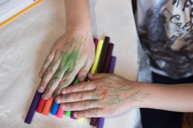 Bir çocuk, elinde farklı renklerde kalemler tutan bir çocuk beyaz arkaplanı kapatıyor.