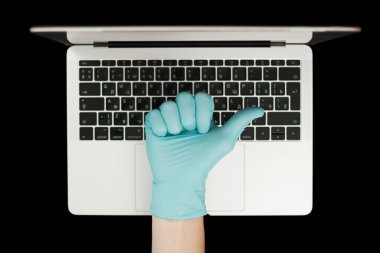 Mavi eldiven, baş parmaklarını gösteriyor. Taşınabilir laptop. Coronavirus koruması. 