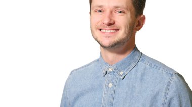 Genç yakışıklı adam mutlu ve şapşal görünüyor. Beyaz arka planda geniş, eğlenceli bir gülüşü var.