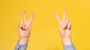 Sarı arka planda parmak izleriyle Zafer İşareti Gösteren Adam Eli