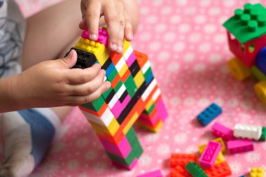 Çocuğun küçük elleri parlak plastik renkli tasarımcıyı toplar. Eğitici oyuncaklar ve erken öğrenim