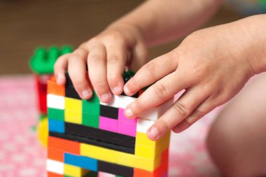 Çocuğun küçük elleri parlak plastik renkli tasarımcıyı toplar. Eğitici oyuncaklar ve erken öğrenim
