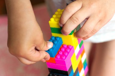 Çocuğun küçük elleri parlak plastik renkli tasarımcıyı toplar. Eğitici oyuncaklar ve erken öğrenim