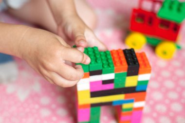 Çocuğun küçük elleri parlak plastik renkli tasarımcıyı toplar. Eğitici oyuncaklar ve erken öğrenim