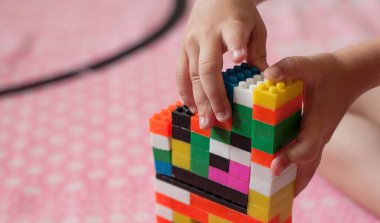 Çocuğun küçük elleri parlak plastik renkli tasarımcıyı toplar. Eğitici oyuncaklar ve erken öğrenim