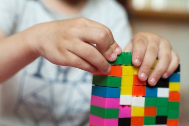 Çocuğun küçük elleri parlak plastik renkli tasarımcıyı toplar. Eğitici oyuncaklar ve erken öğrenim