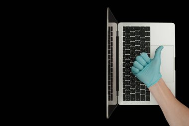 Mavi eldiven, baş parmaklarını gösteriyor. Taşınabilir laptop. Coronavirus koruması. 
