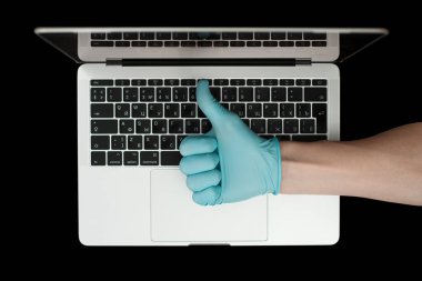 Mavi eldiven, baş parmaklarını gösteriyor. Taşınabilir laptop. Coronavirus koruması. 