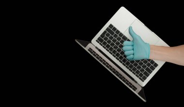 Mavi eldiven, baş parmaklarını gösteriyor. Taşınabilir laptop. Coronavirus koruması. 