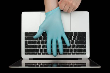 Eller dizüstü bilgisayarda yazan mavi koruyucu eldivenlerle. Üst Manzara. Coronavirus konsepti.