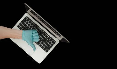 Mavi eldiven, baş parmaklarını gösteriyor. Taşınabilir laptop. Coronavirus koruması. 
