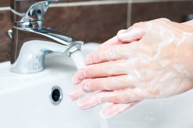 Hijyen konsepti. Musluğun altında sabunla ellerini yıkamak, suyla.